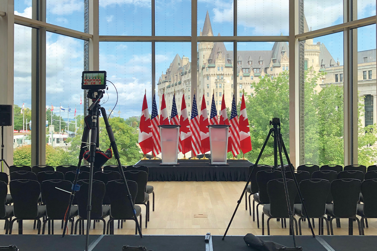Meeting room with stage, podium, and flags with Ottawa landscape in background